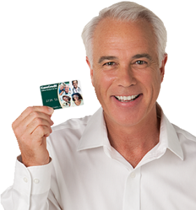 Smiling older gentleman holding up his Care Credit card to show financing options available.