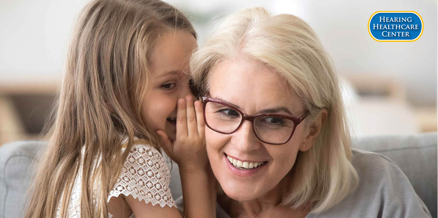 child whispering to her grandma showing the value of communication for May is better hearing and speech month